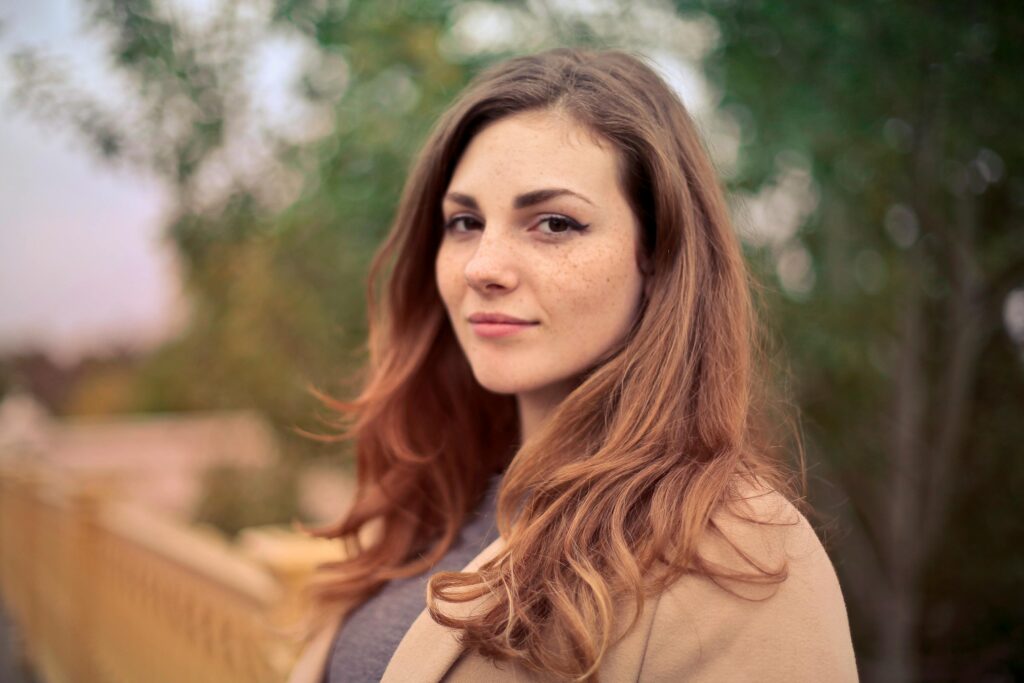 pexels-photo-733872-733872 A young woman with long hair smiles confidently for an outdoor portrait session.